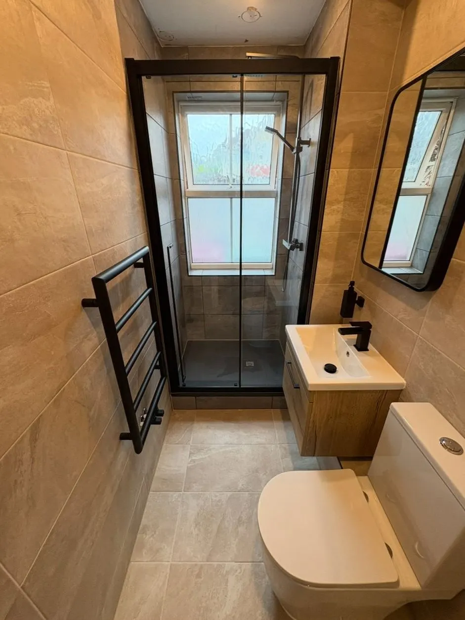 En-suite shower installation with black framed enclosure, slate-effect tray and oak basin unit