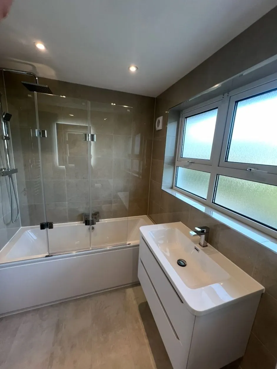 Bathroom refit with shower bath, folding glass screen and wide wall-hung basin unit