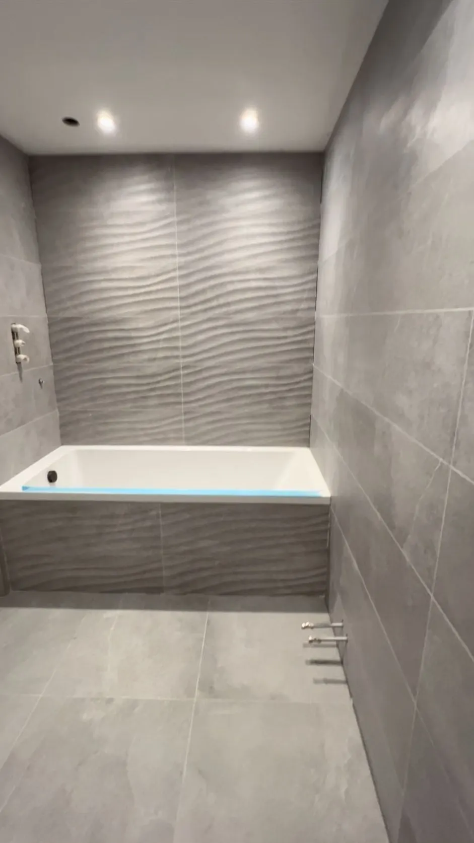 Bathroom renovation in progress with new bath and textured wall tiles, Reading