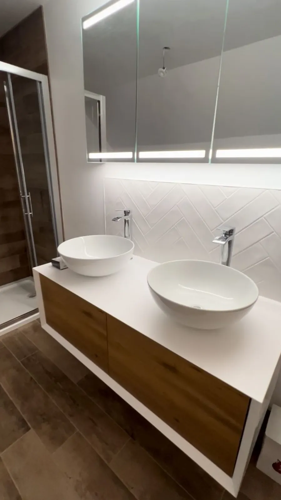Double countertop basins on floating oak vanity with herringbone splashback, bathroom renovation