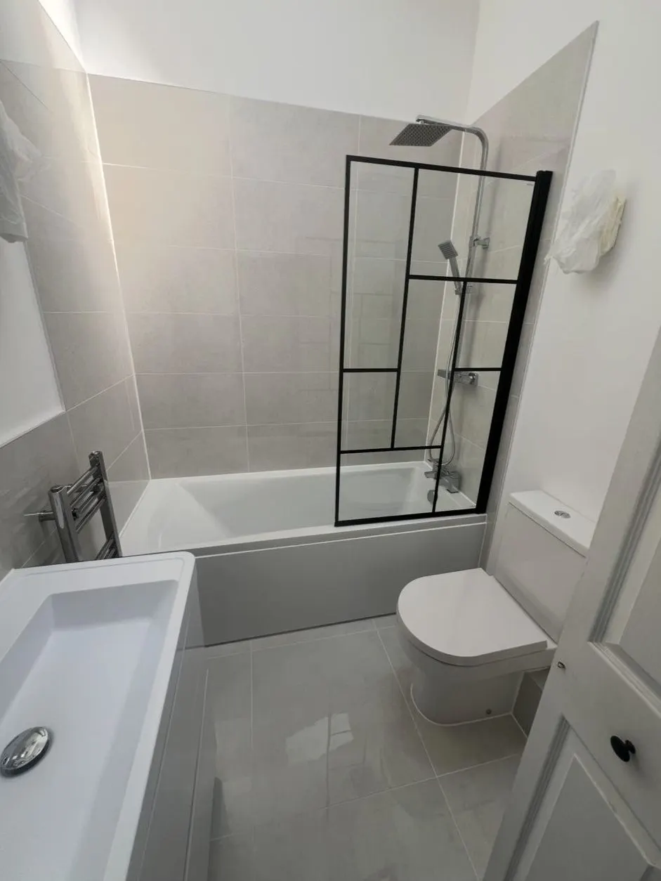 Bathroom installation with shower over bath, black framed screen and rainfall shower head