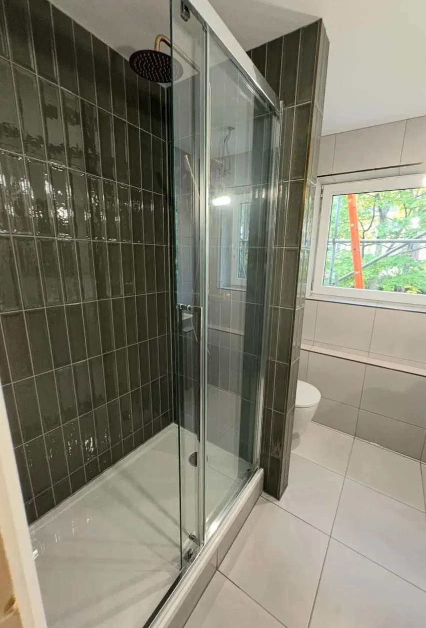 Shower installation with sliding glass door and green vertical gloss tiles, Reading
