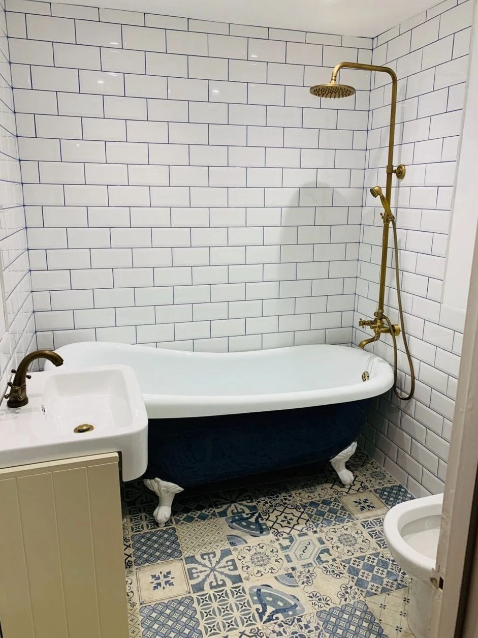 Period bathroom renovation with clawfoot slipper bath, brass exposed shower and metro tiles